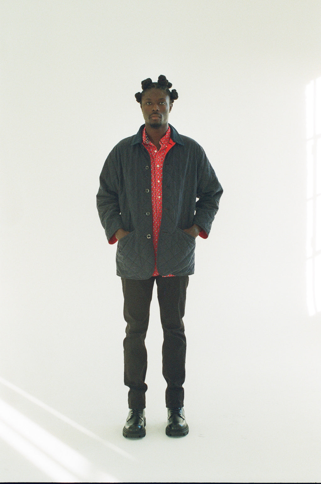 Person wearing a black jacket with a red interior, black pants, and black shoes on a white background