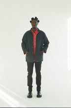 Person wearing a black jacket with a red interior, black pants, and black shoes on a white background