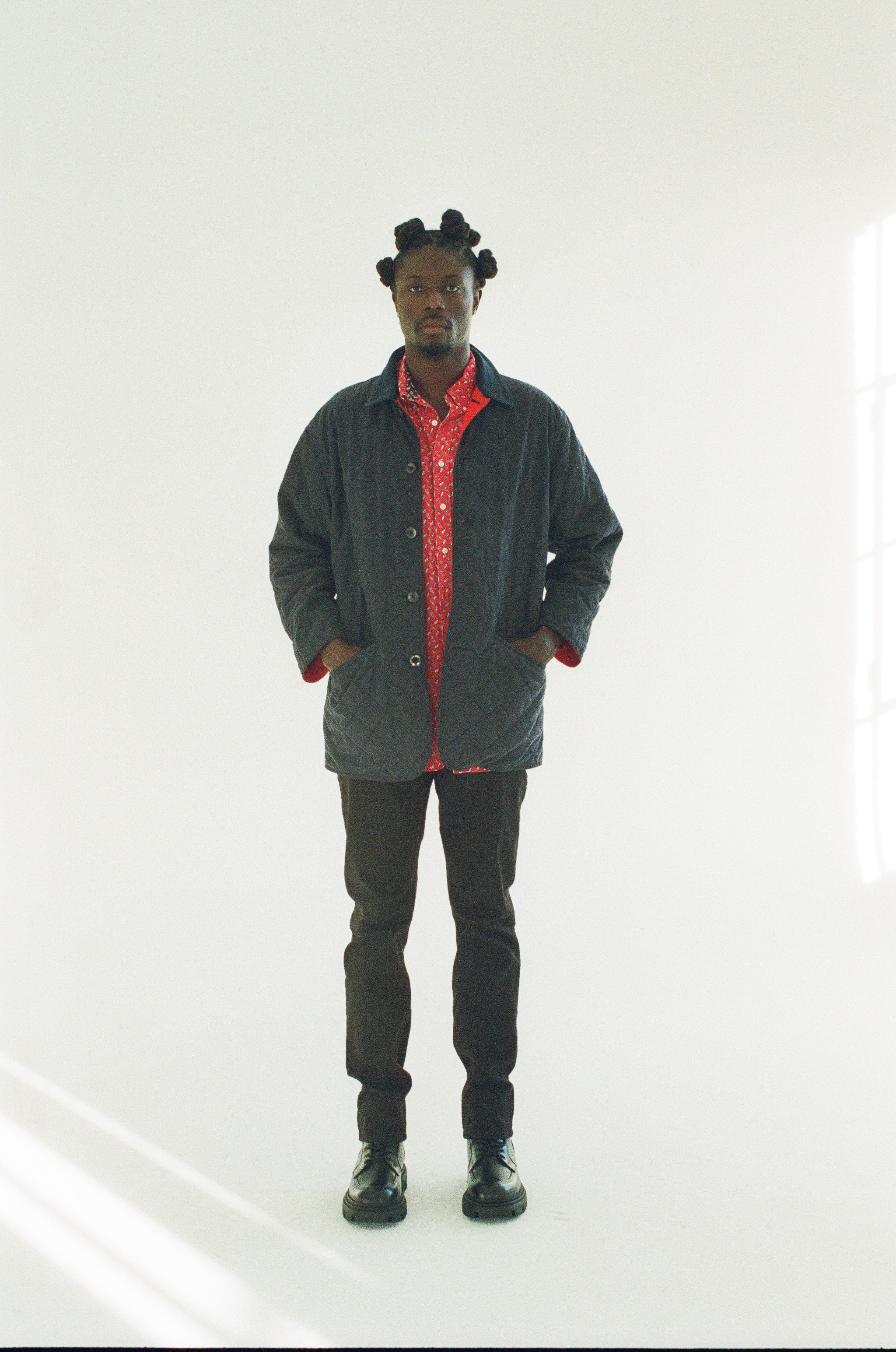 Person wearing a black jacket with a red interior, black pants, and black shoes on a white background