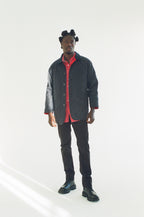 Man wearing a black acket and red shirt with a white background