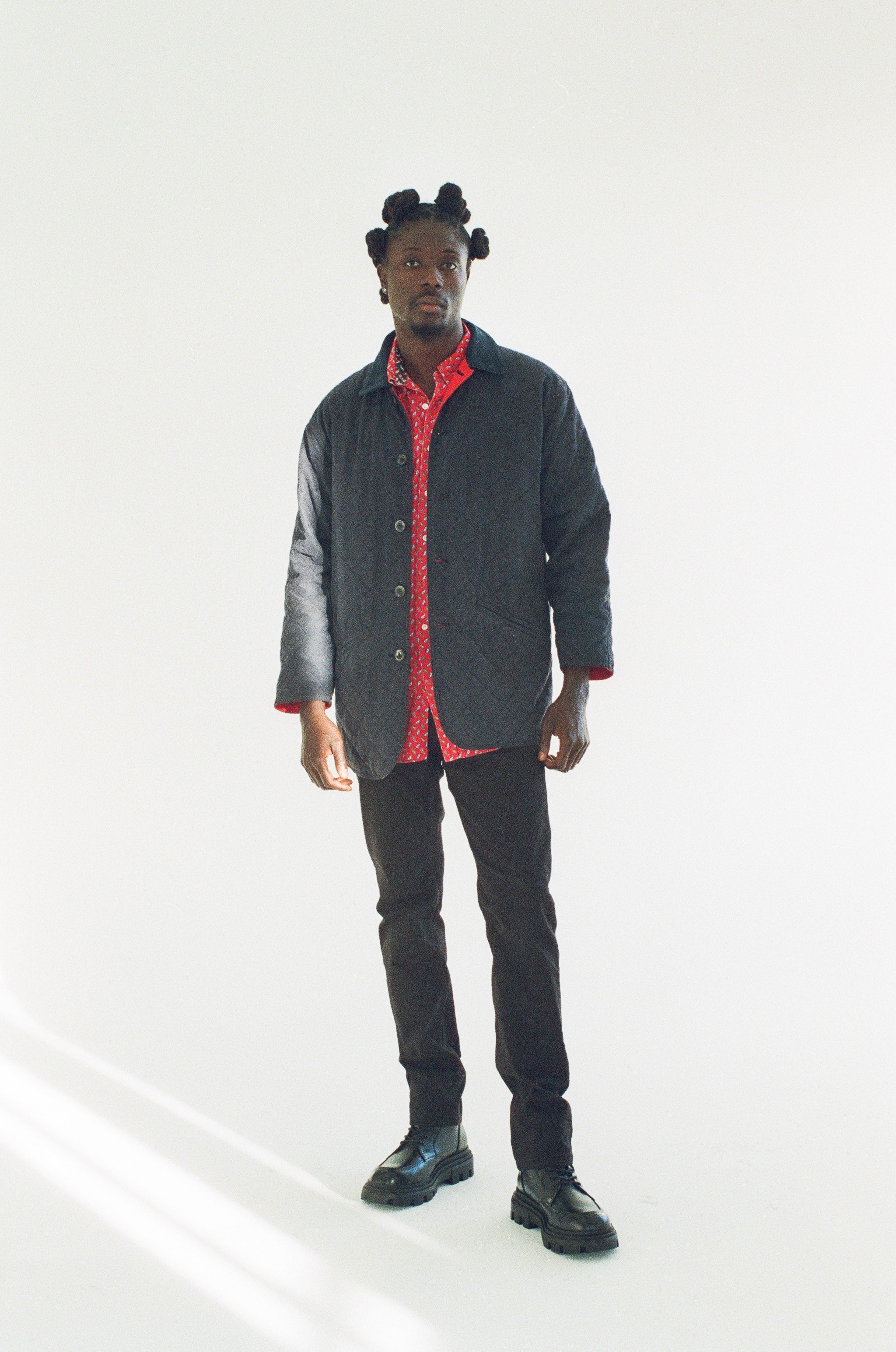 Man wearing a black acket and red shirt with a white background