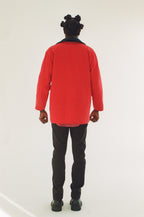 Person wearing a red coat and black pants on a white background