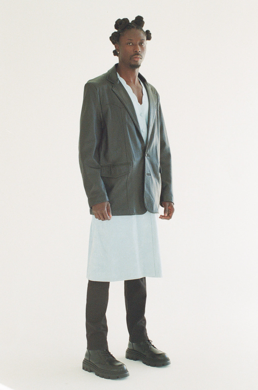 Person wearing a black blazer over a white dress on a white background