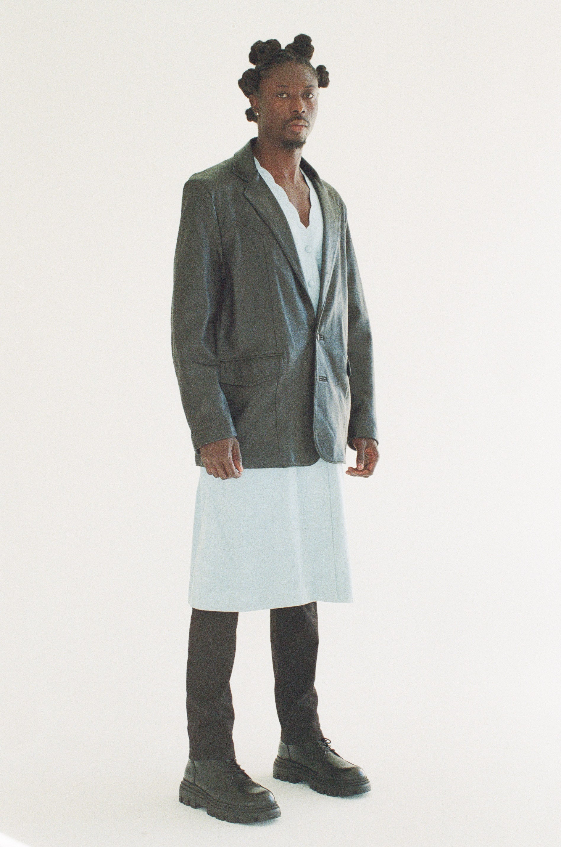 Person wearing a black blazer over a white dress on a white background