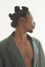 Man with styled hair wearing a black blazer against a white background
