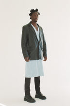 Man wearing a long black blazer over a white shirt on a white background