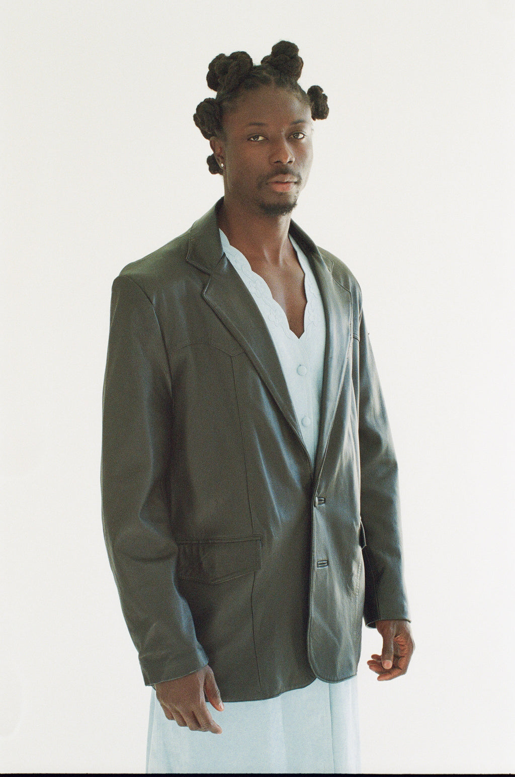 Man wearing a black blazer over a white shirt on a white background