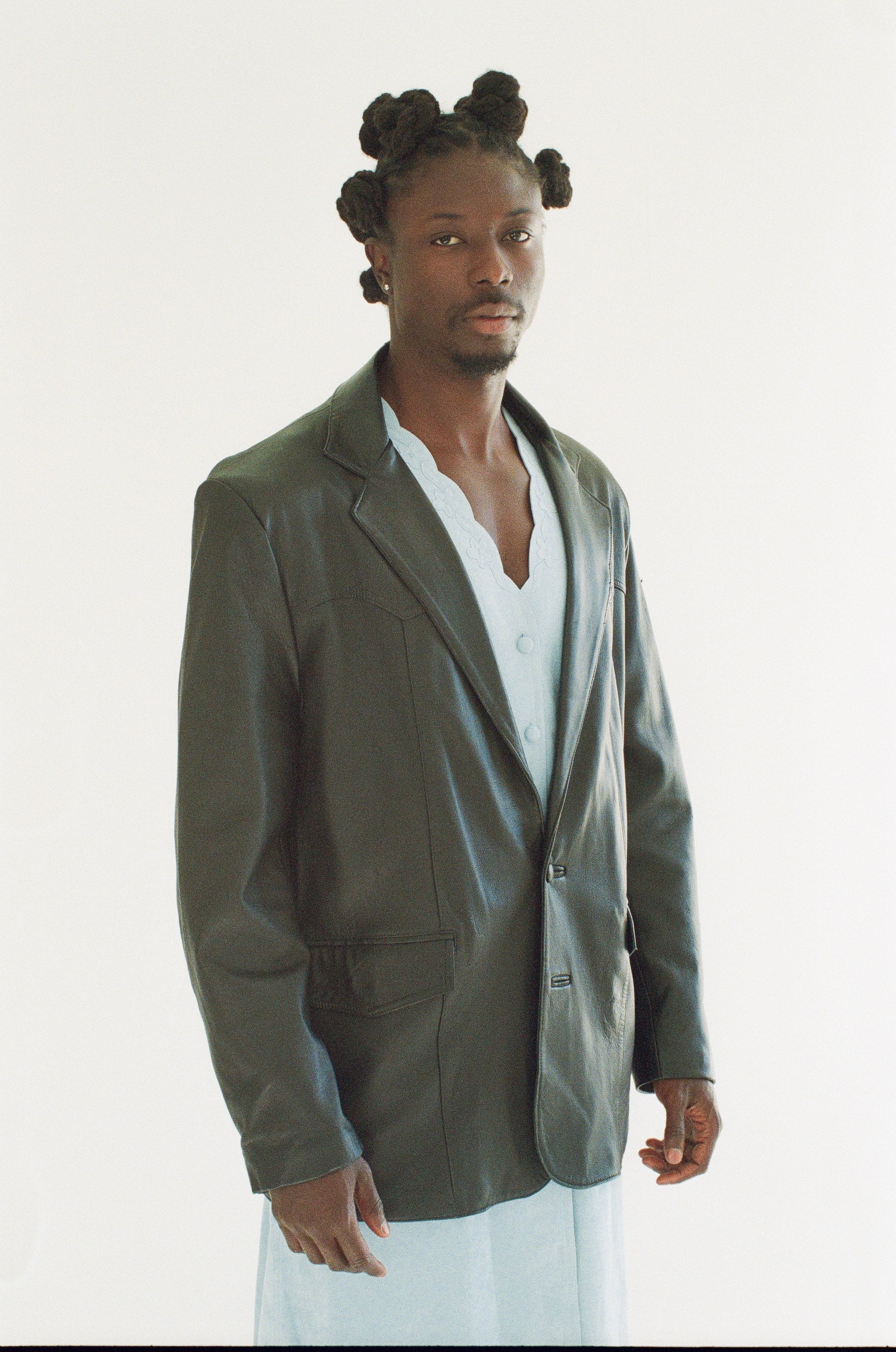 Man wearing a black blazer over a white shirt on a white background