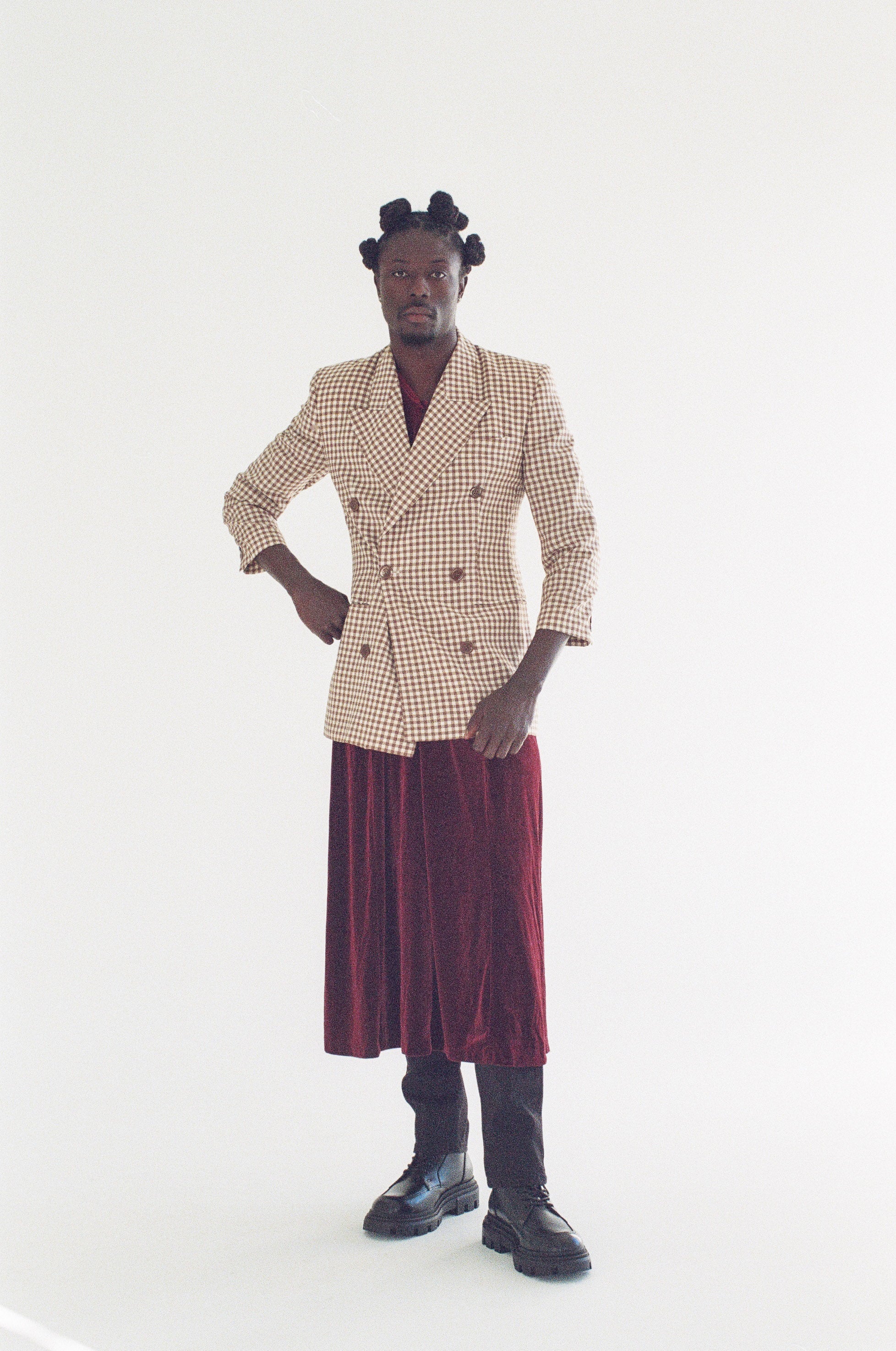 Person wearing a patterned blazer and red skirt on a white background