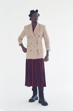 Person wearing a patterned blazer and skirt on a white background