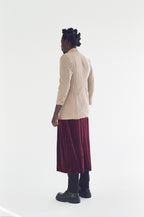 Person wearing a beige checkered shirt and burgundy skirt on a white background