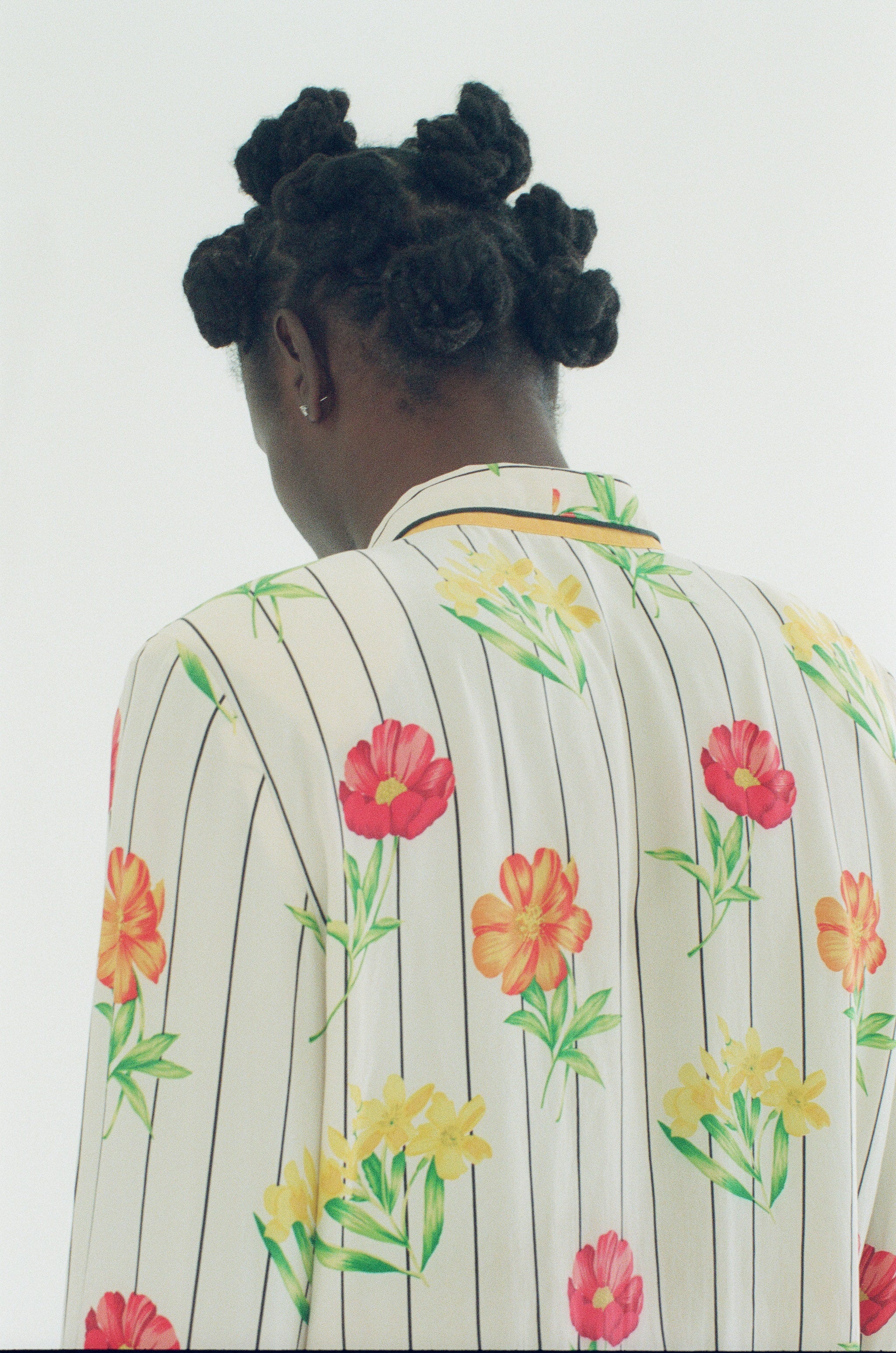Person wearing a floral-patterned outfit with a plain background