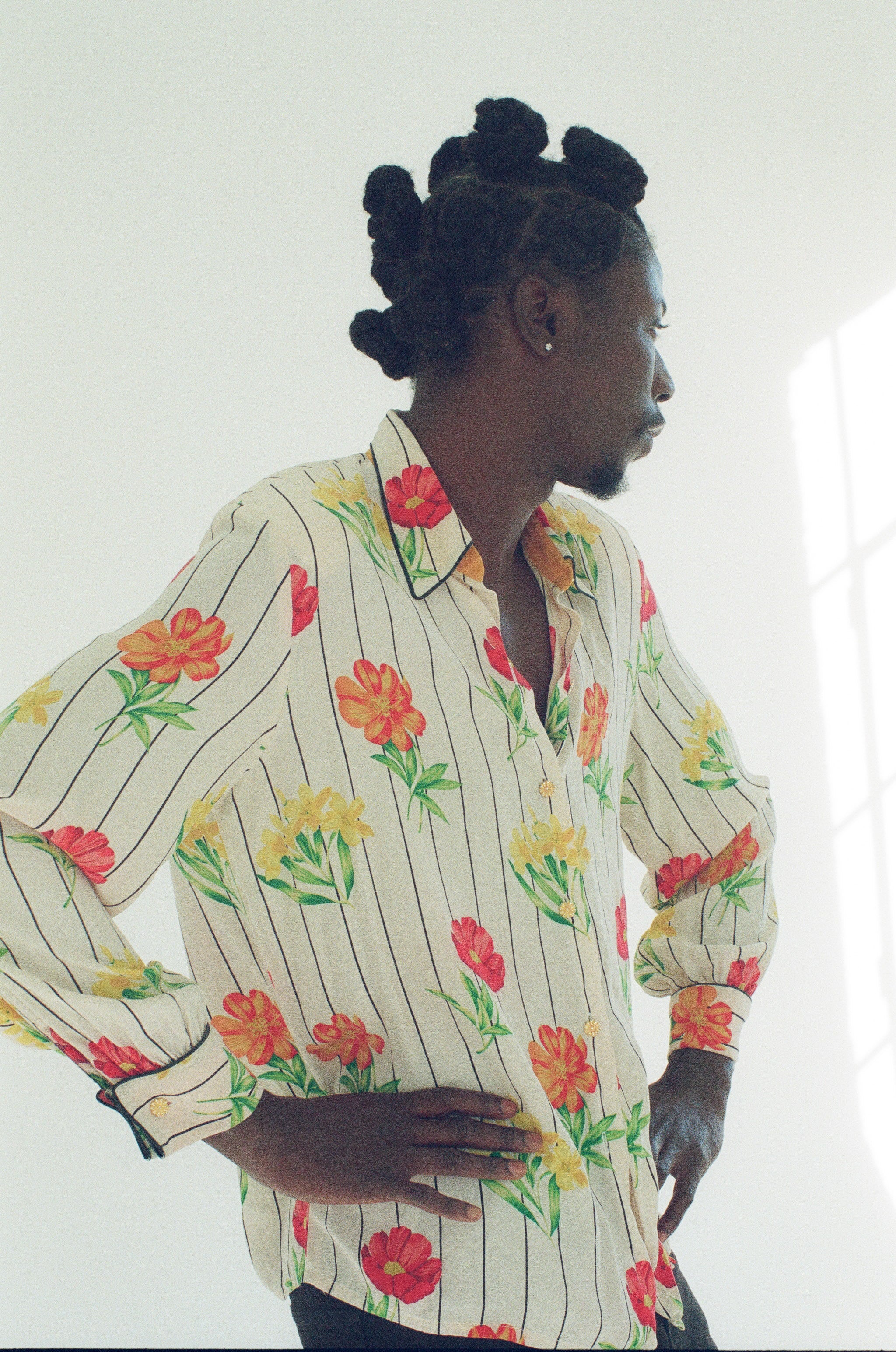 Person wearing a colorful floral shirt with vertical stripes on a white background