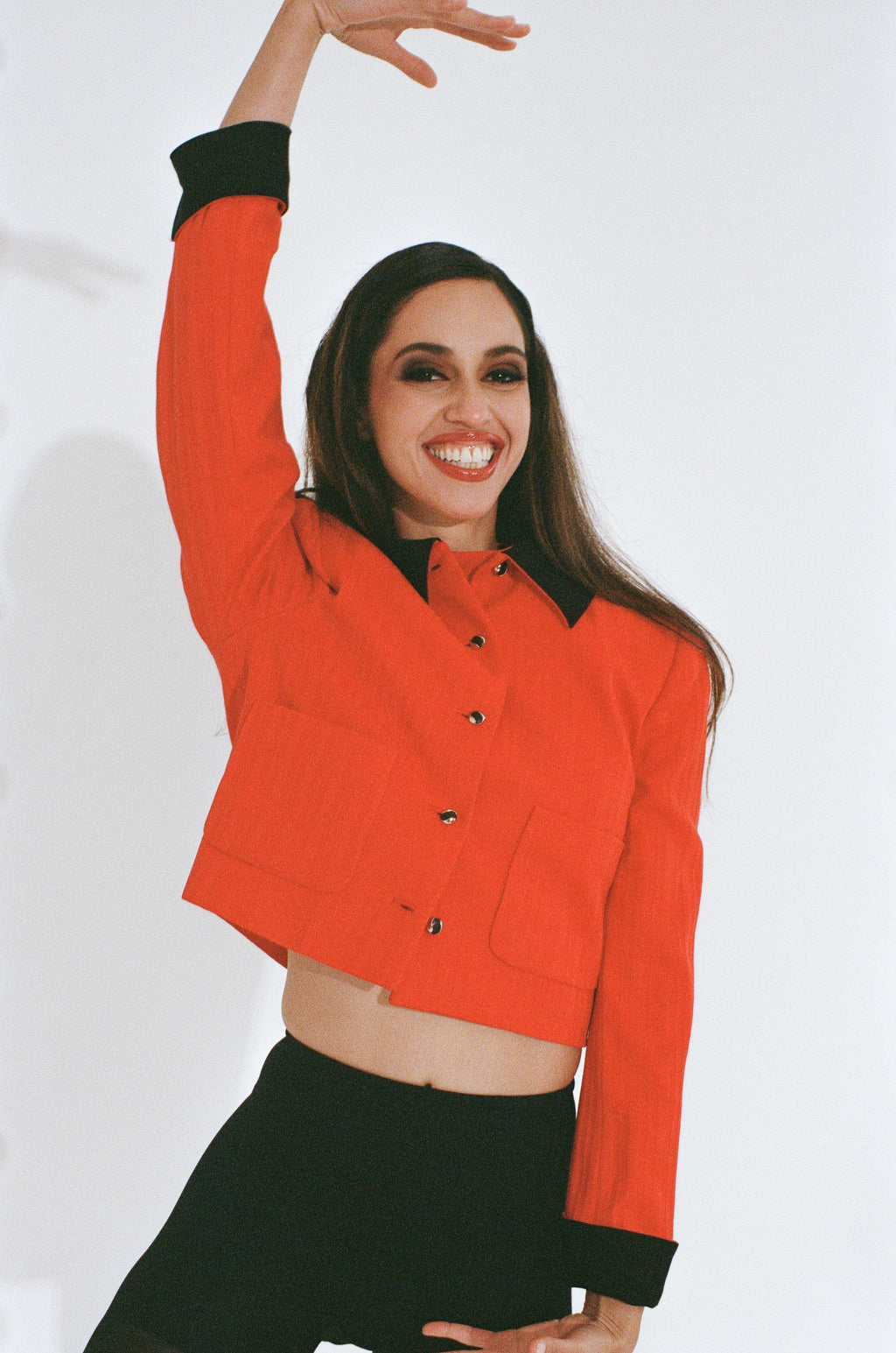 Woman wearing a red jacket with black cuffs and collar on a white background