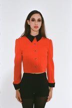 Woman wearing a red blouse with black collar and cuffs on a white background