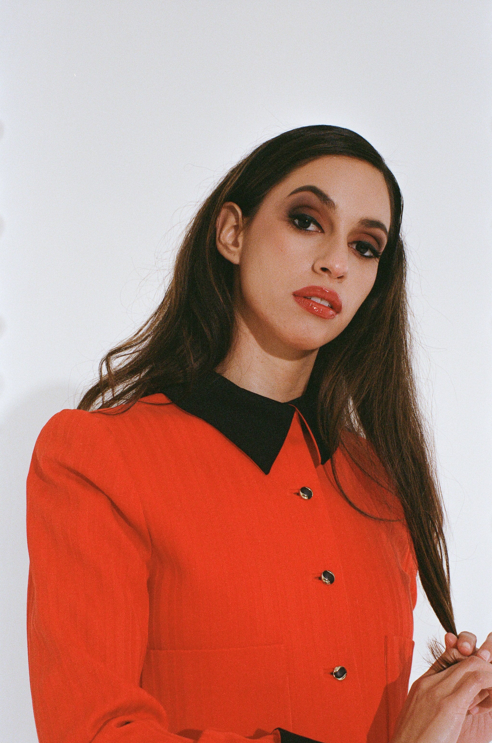 Woman wearing a red blouse with a black collar against a white background