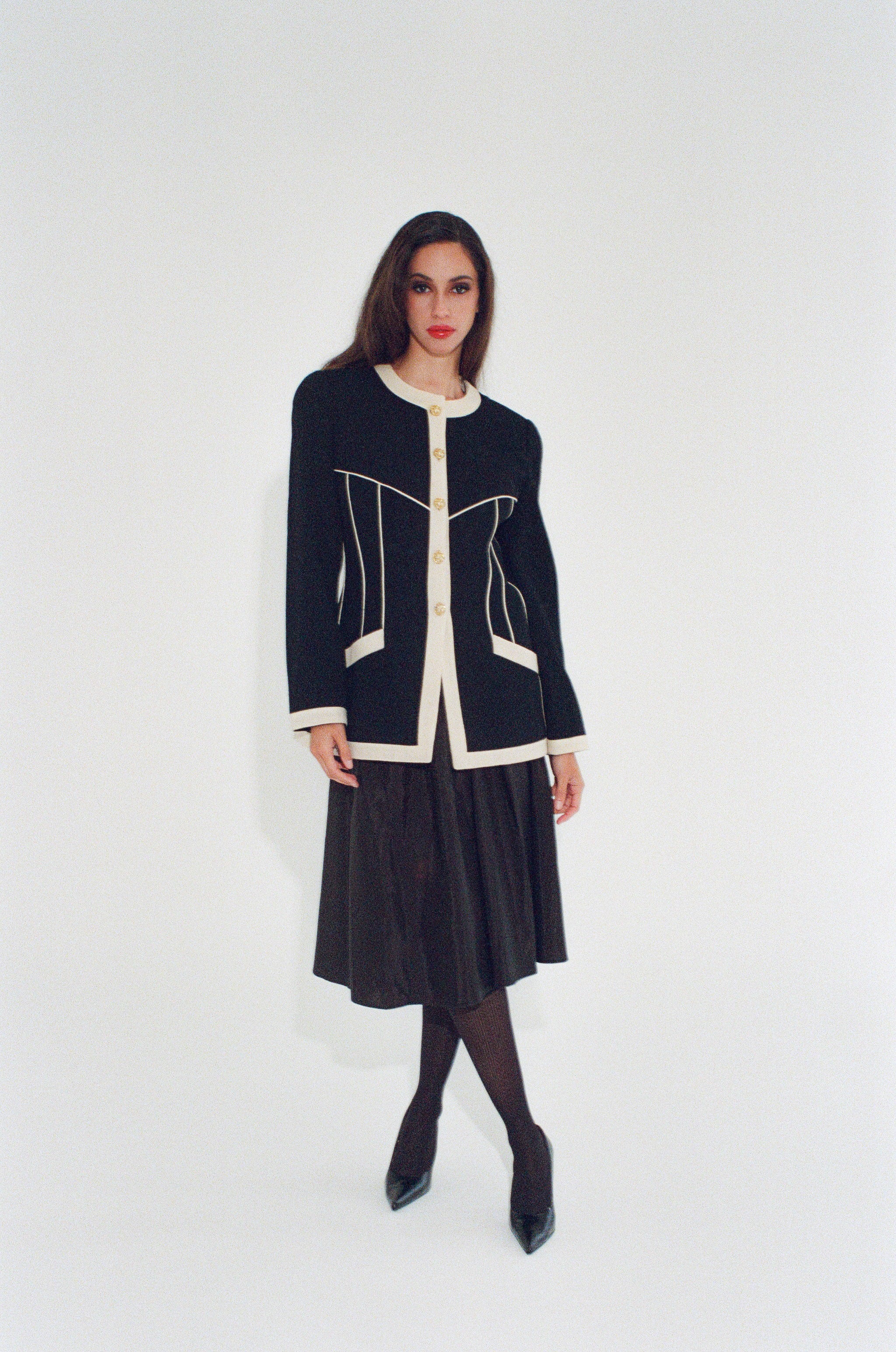 Woman wearing a black and white jacket with a black skirt on a white background