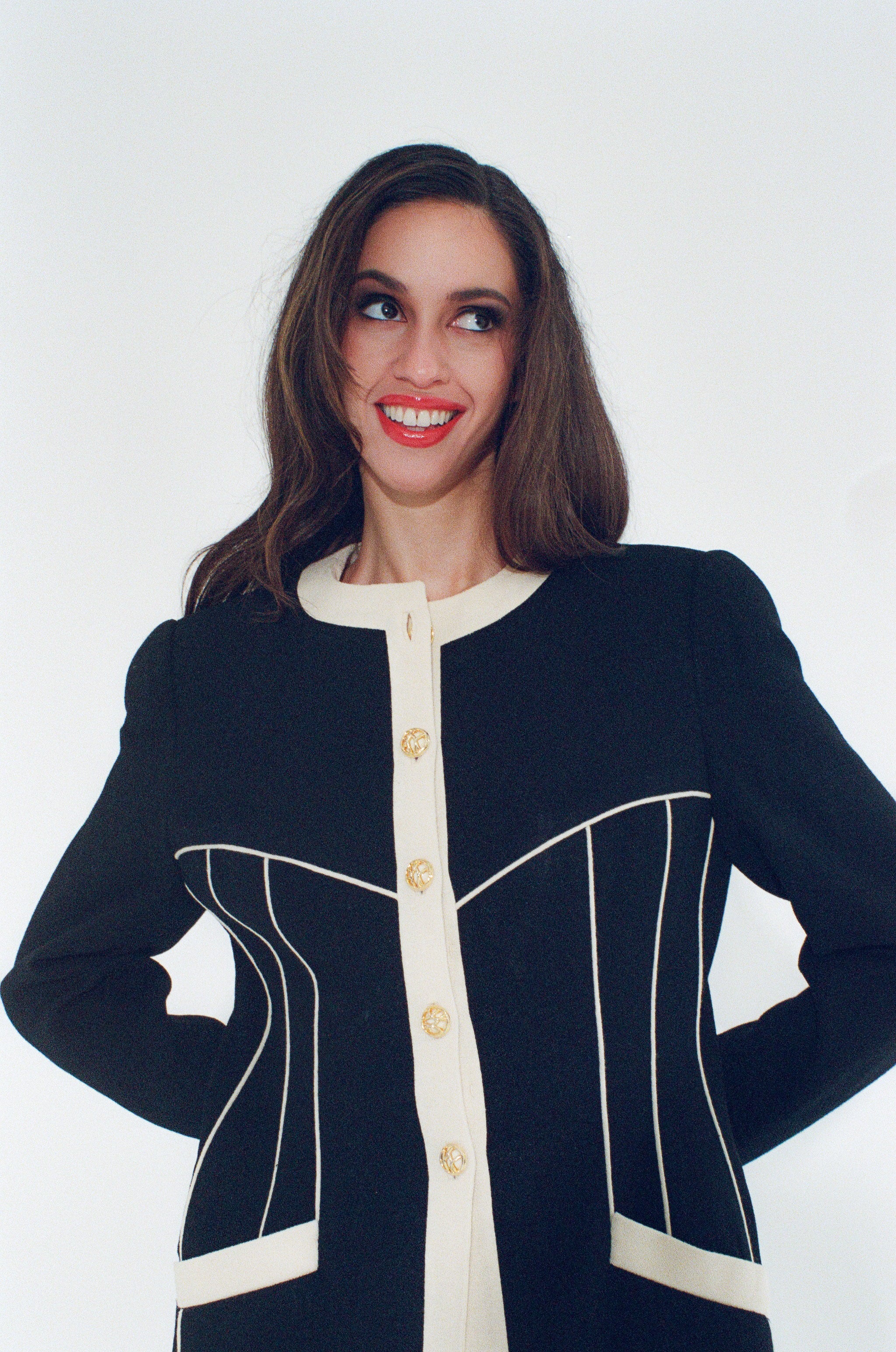 Woman wearing a black and white jacket with gold buttons on a white background