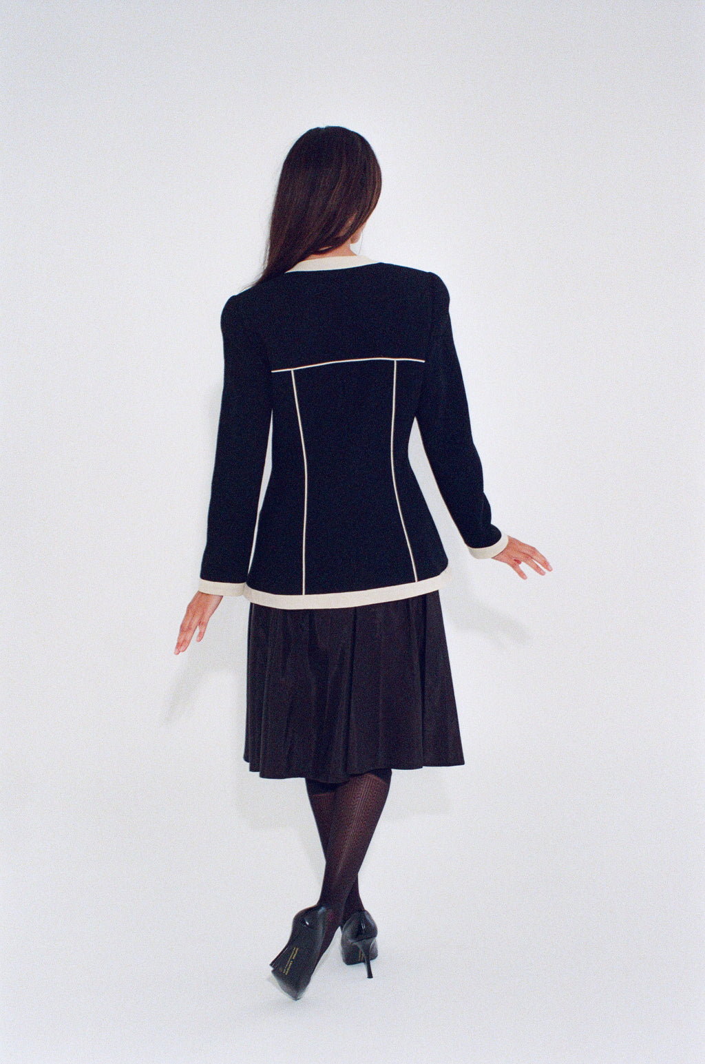Woman wearing a black dress with white trim on a white background