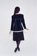 Woman wearing a black dress with white trim on a white background