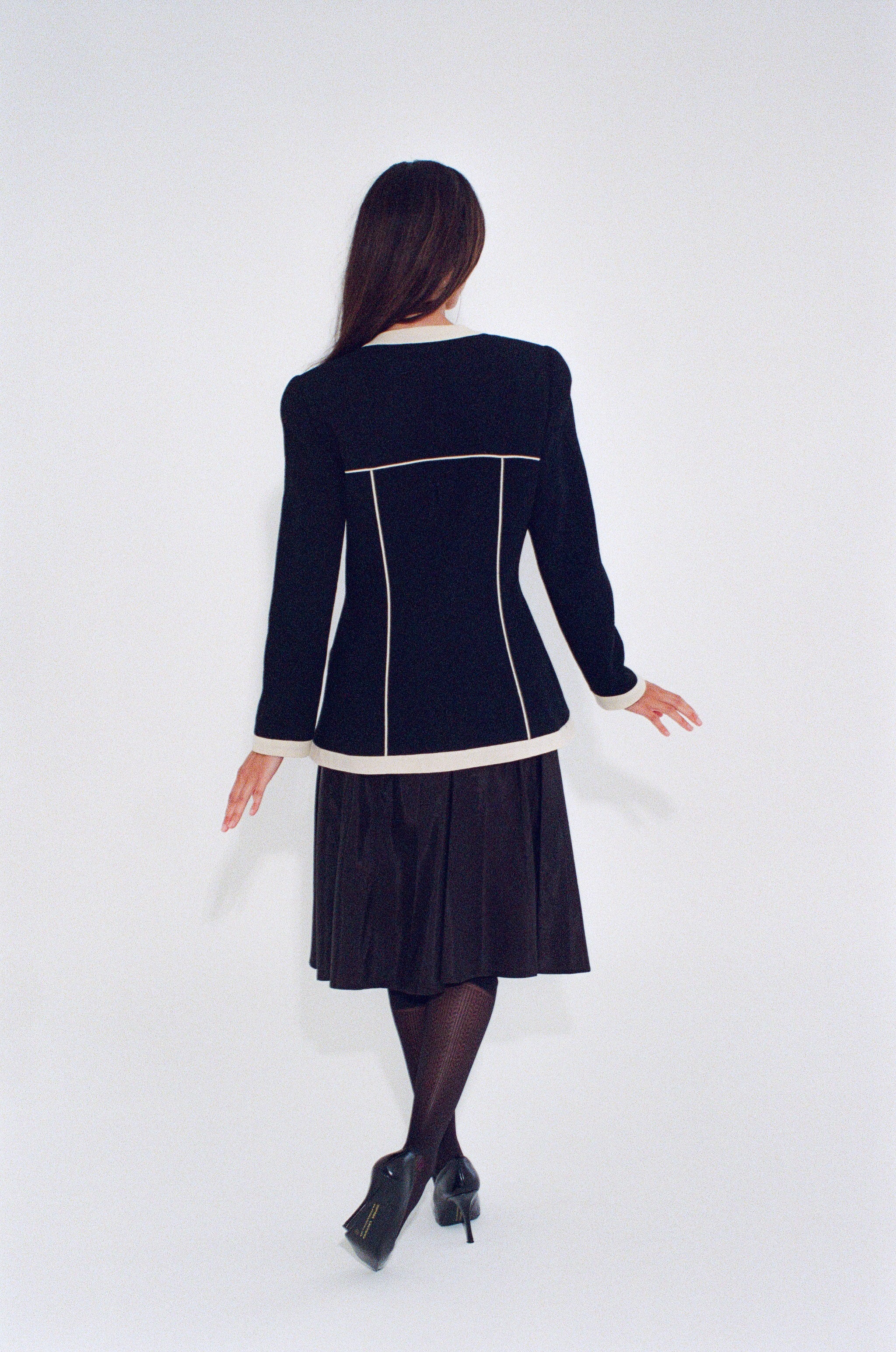 Woman wearing a black dress with white trim on a white background