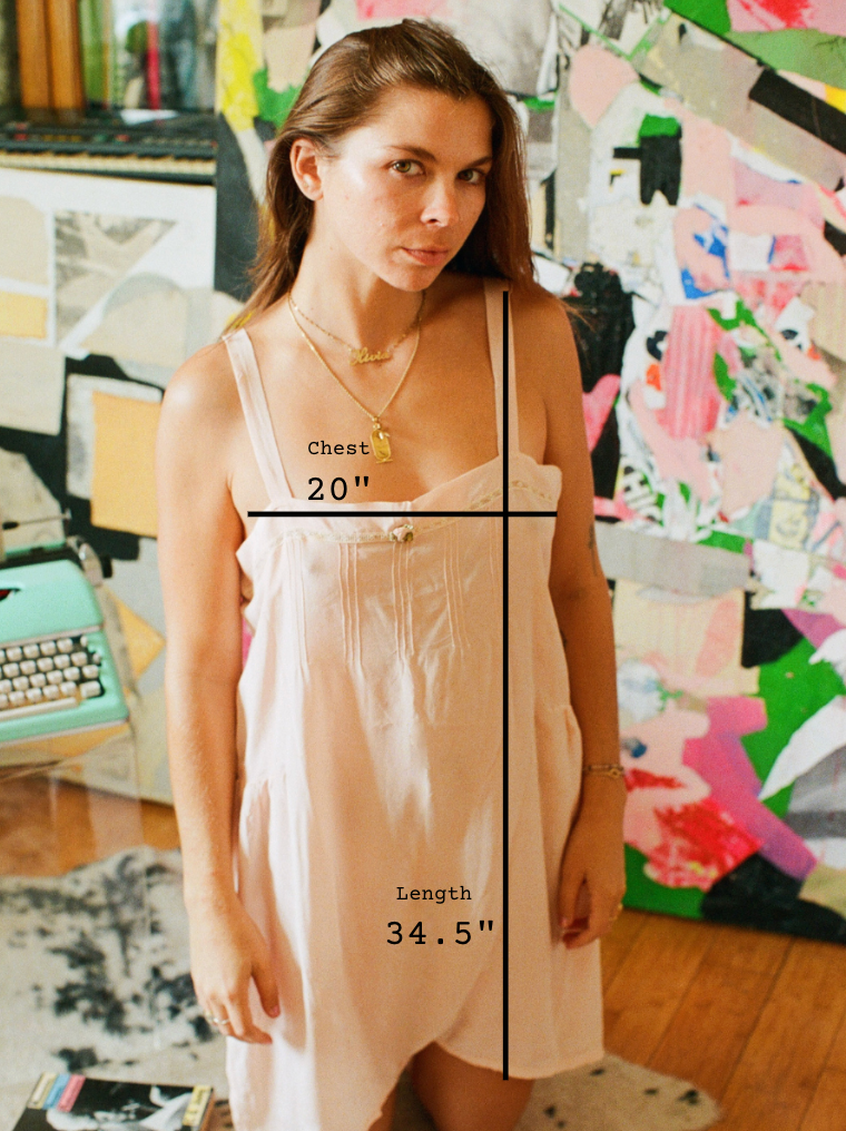 Woman wearing a dress with measurements labeled in front of a colorful abstract painting.