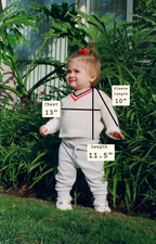 Child wearing a sweater with measurements labeled, standing outdoors.