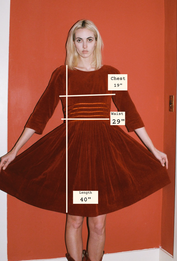 Woman wearing a red dress with measurements labeled on an orange wall.
