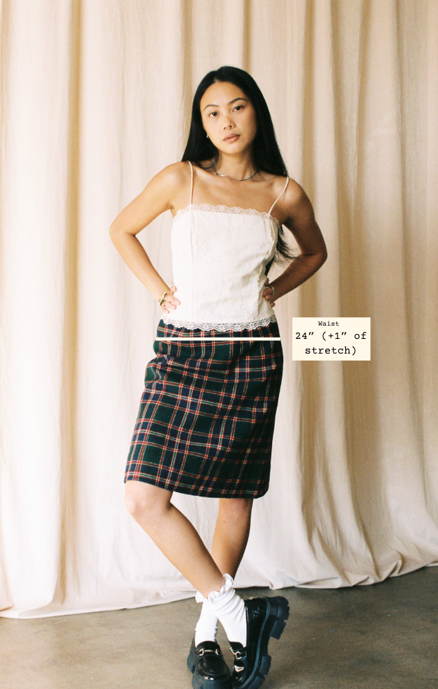 Woman wearing a white top and plaid skirt against a plain background