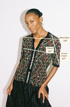 Model wearing a patterned shirt with measurements labeled on a white background