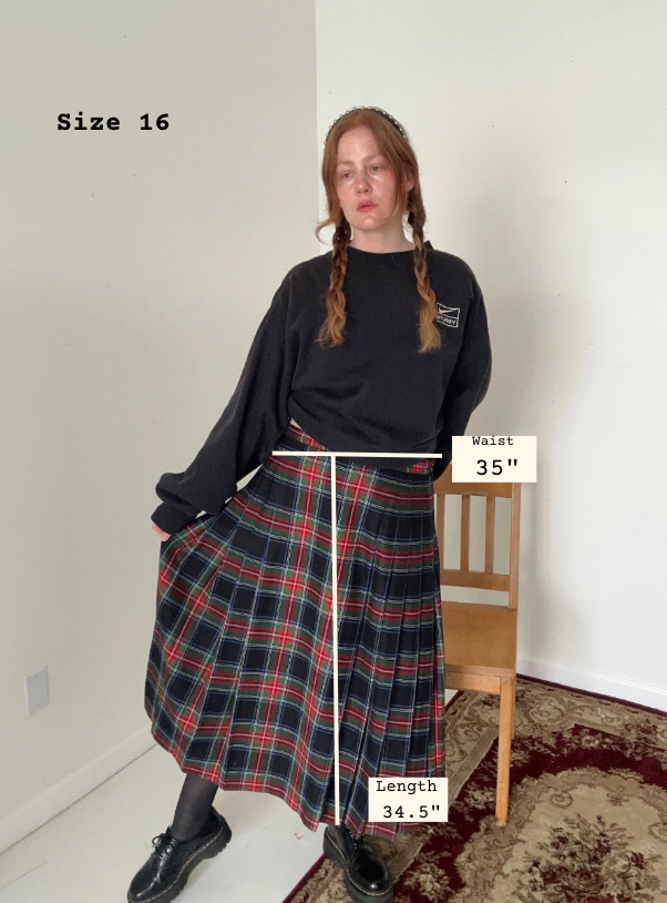 Person wearing a black sweater and plaid skirt with measurements labeled, standing indoors.