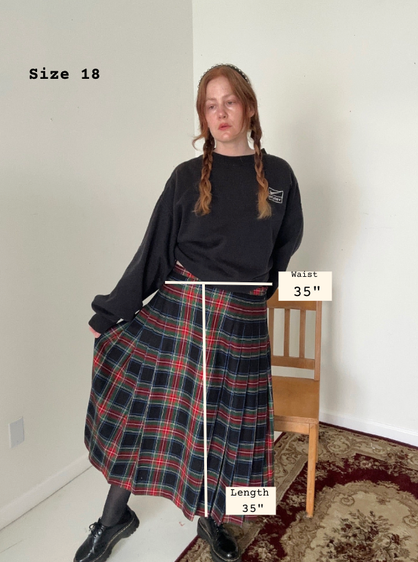 Person wearing a plaid skirt with measurements labeled, standing against a white wall.