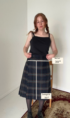 Woman wearing a plaid skirt with measurements labeled on a plain background