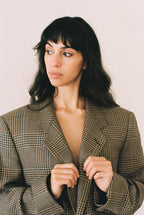 Woman wearing a plaid blazer against a plain background