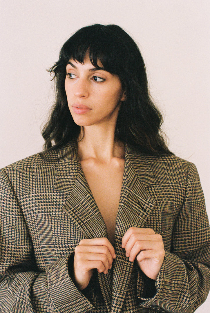 Woman wearing a plaid blazer against a plain background