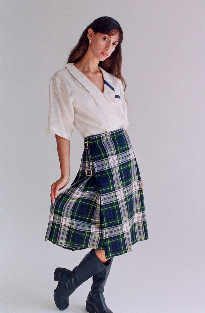 Woman wearing a white blouse and plaid skirt on a plain background