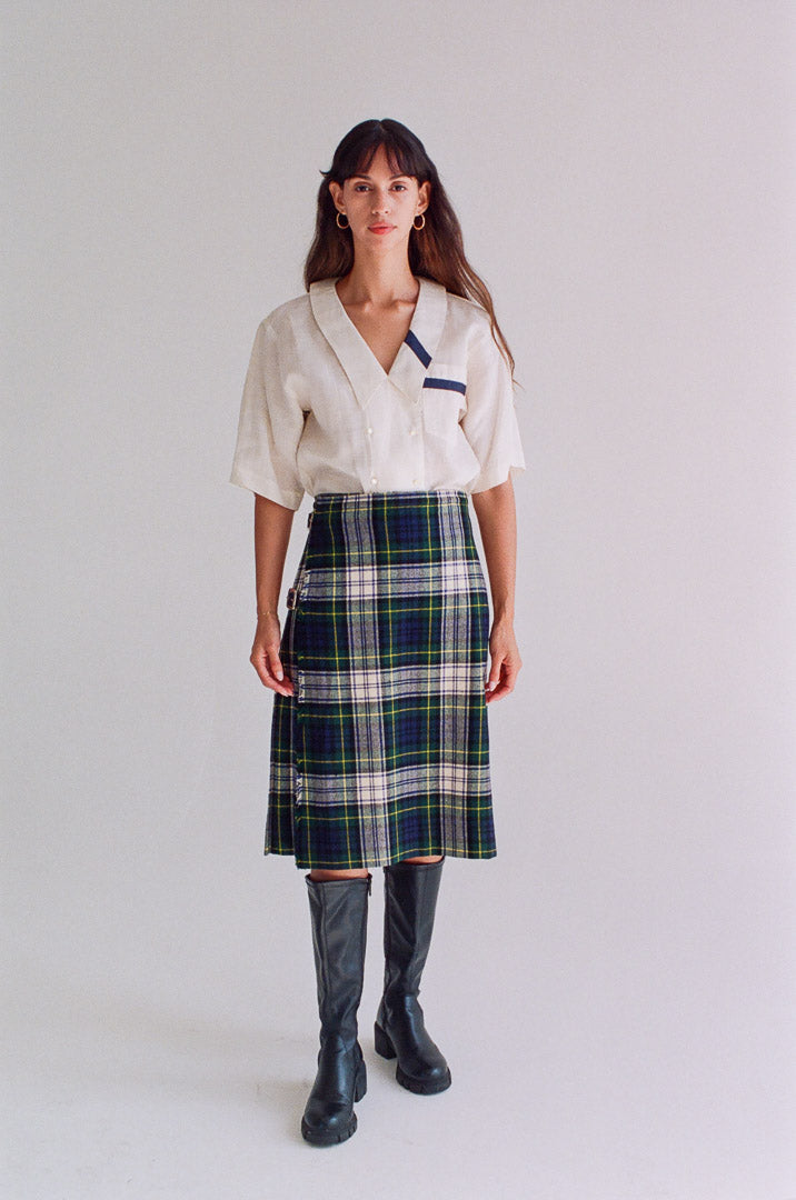 Woman wearing a white blouse with a blue plaid skirt on a plain background