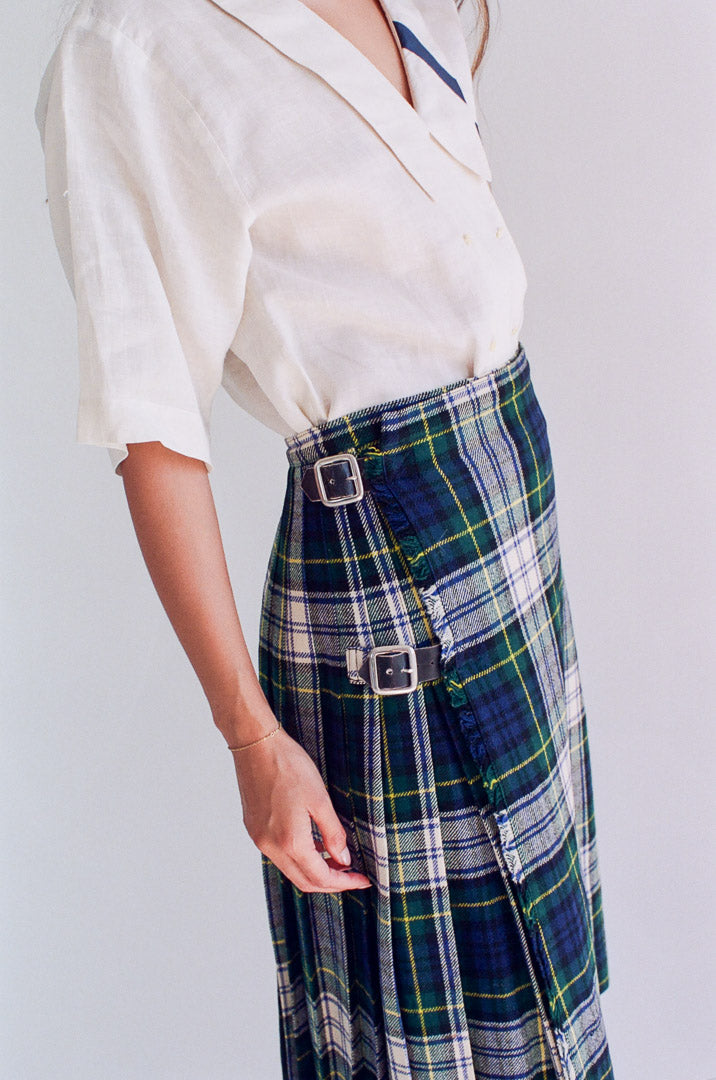 Person wearing a white blouse and plaid skirt on a plain background