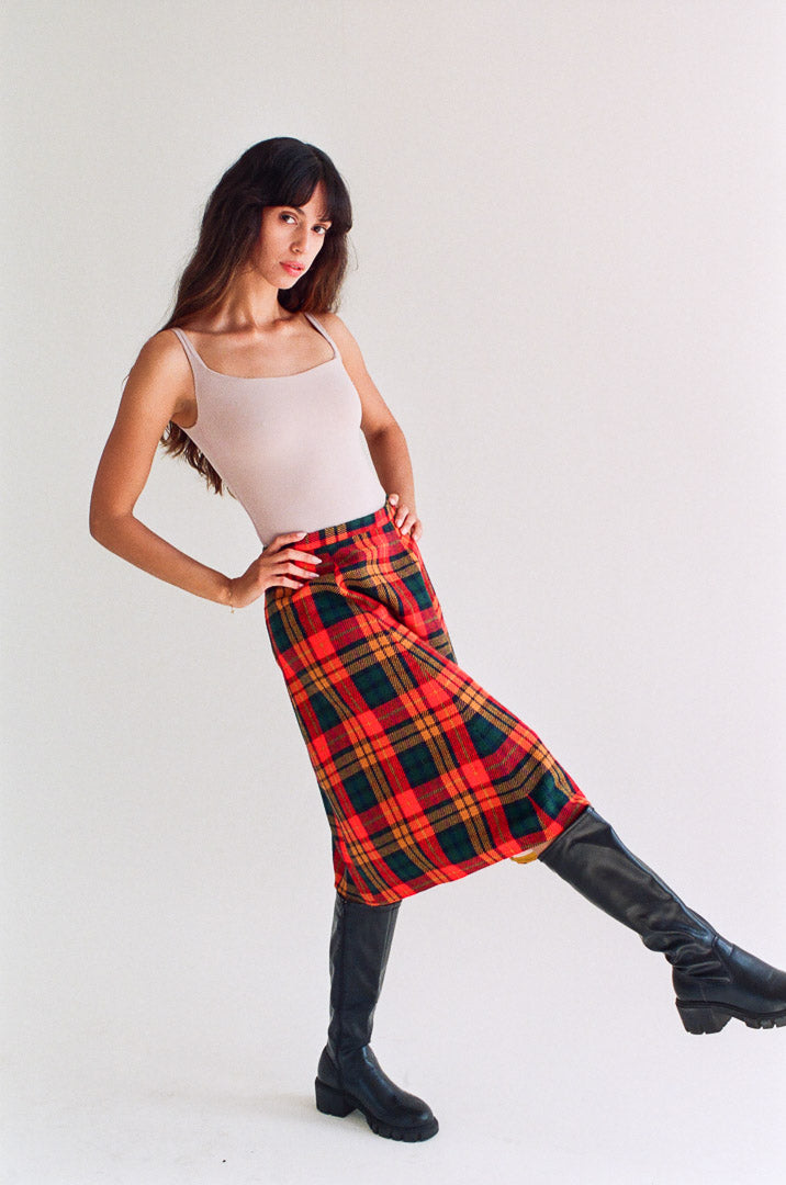 Woman wearing a red plaid skirt and black knee-high boots on a white background