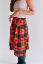 Person wearing a red and green plaid skirt on a white background