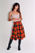 Woman wearing a plaid skirt with a plain background