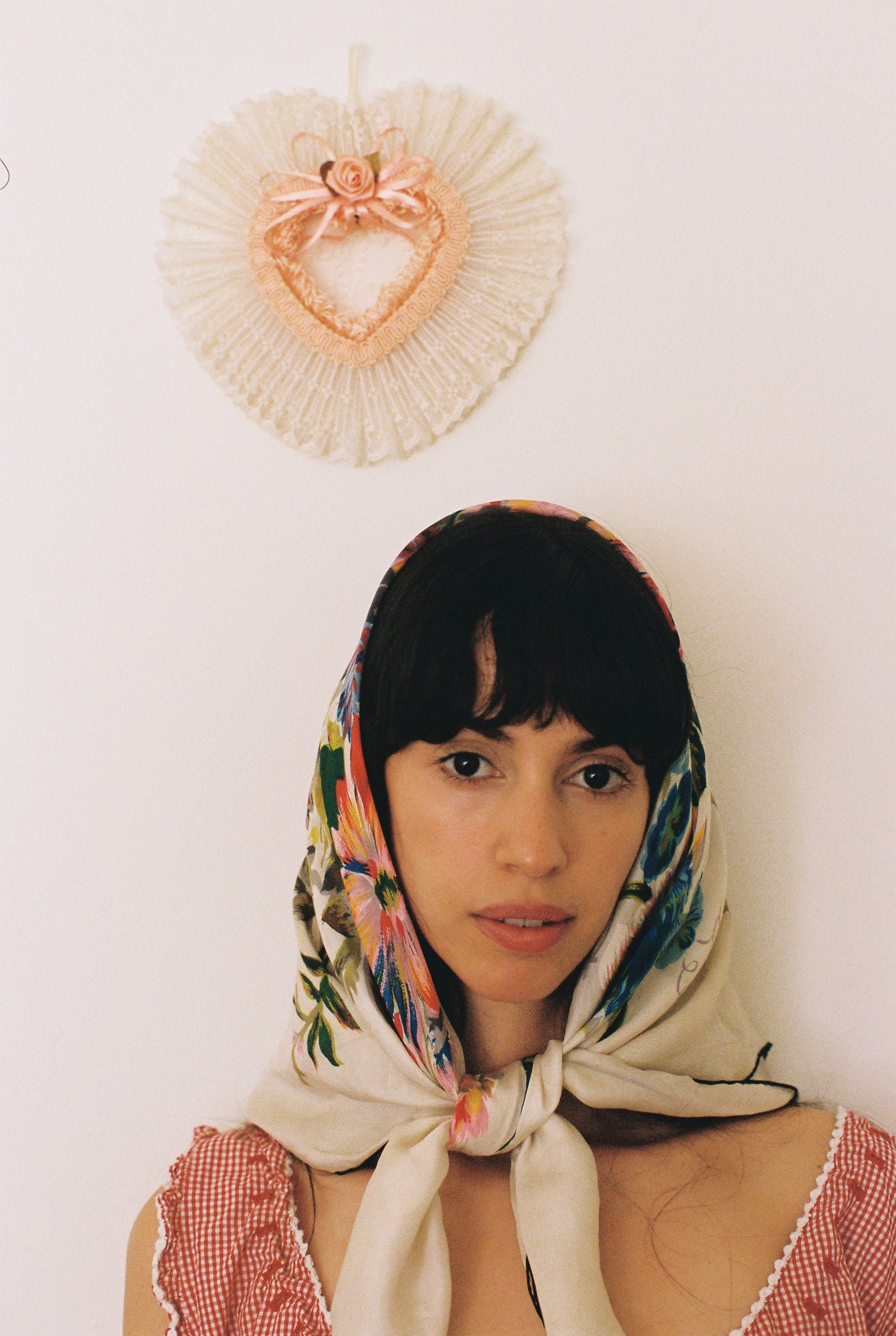 Woman wearing a colorful headscarf with decorative wall art in the background