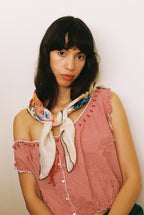 Woman wearing a red checkered top with a colorful scarf, against a plain background