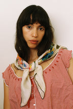 Woman wearing a colorful scarf and red checkered dress against a plain background