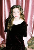 Woman in a black dress with a pink curtain background