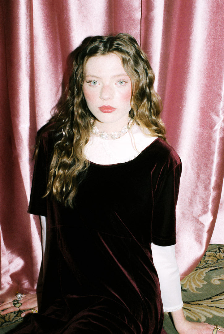 Woman in a black dress with a pink curtain background