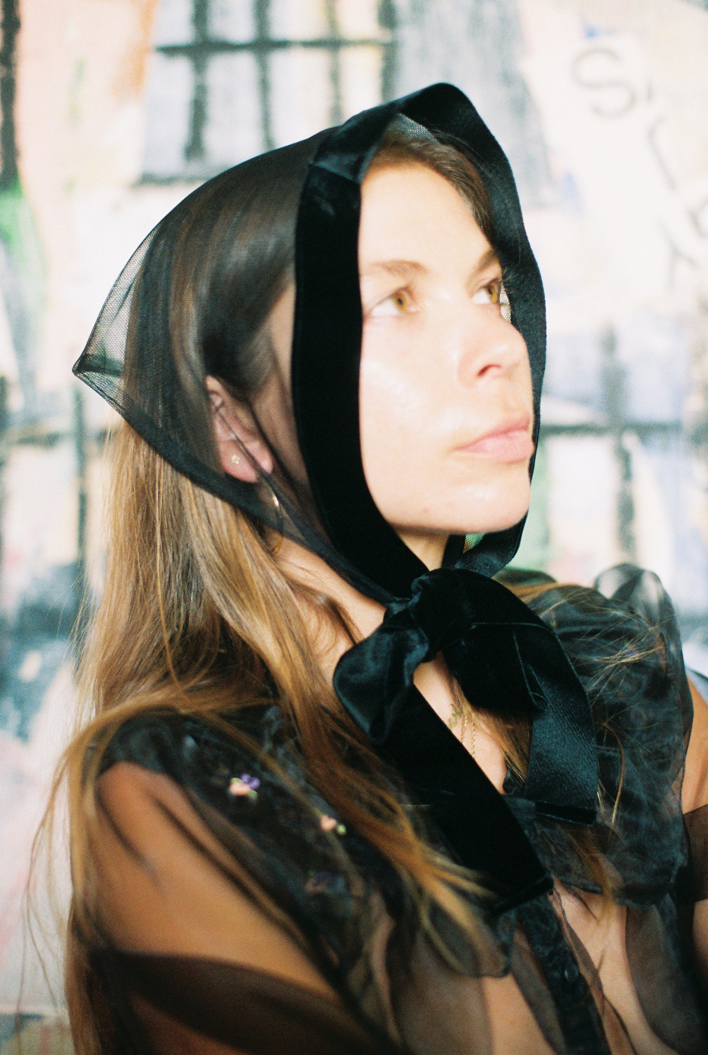 Woman wearing a black sheer bonnet with a large bow in an outdoor setting