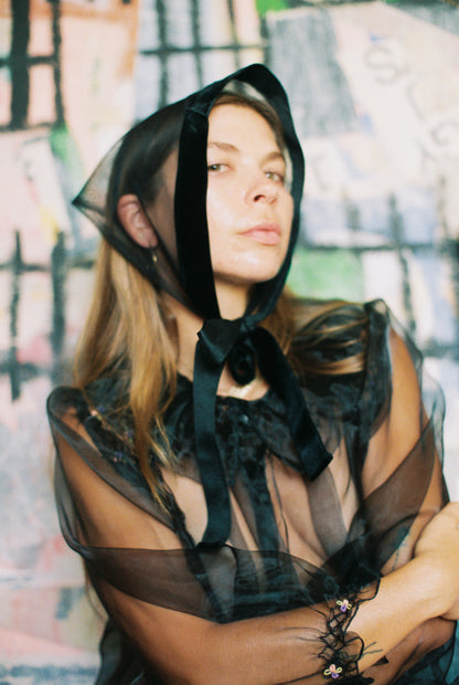 Person wearing a black sheer bonnet with a blurred background