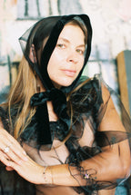 Woman wearing a black sheer scarf with a blurred background