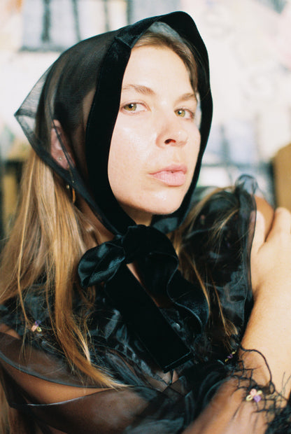 Woman wearing a black hooded garment with sheer overlay
